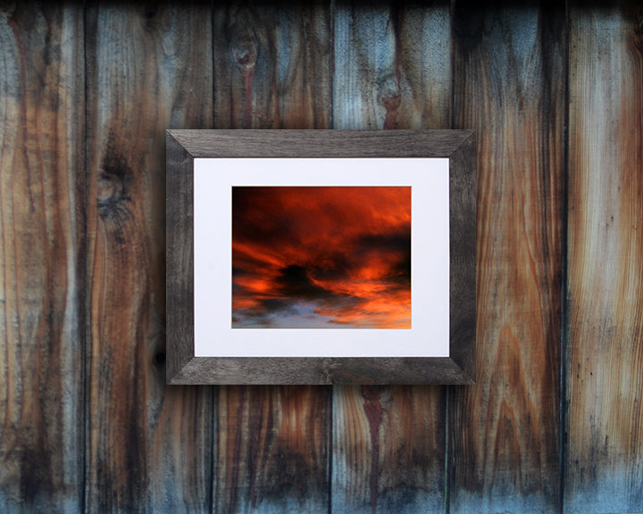 Nature photography print of a fiery sunset with orange and black clouds shown mounted with a black frame called Burst by Loud Hue