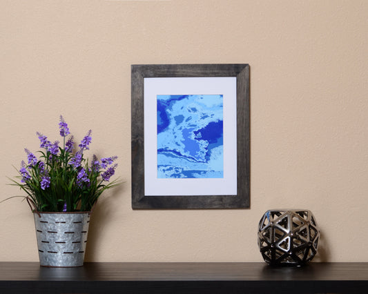 Vibrant Abstract Art Print in the form of waves with hues of blues shown with a black frame called Boundless by Loud Hue