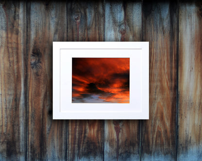 Nature photography print of a fiery sunset with orange and black clouds shown mounted with a white frame called Burst by Loud Hue