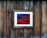 Nature photography print of a glowing red sunset shown mounted with a black frame called Cotton Candy by Loud Hue