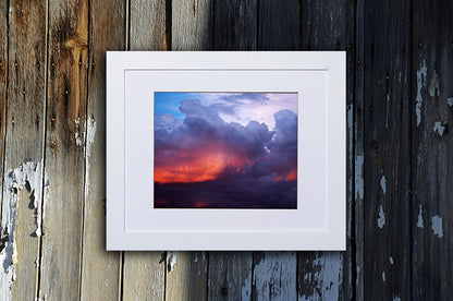 Nature photography print of a turbulent multicolor sunset shown with a white frame called Divine by Loud Hue